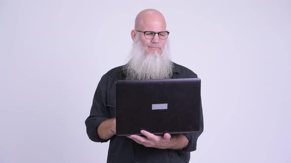 Happy Mature Bald Bearded Man Using Laptop