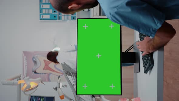 Vertical Video Assistant Looking at Horizontal Green Screen on Computer
