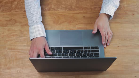 Man opening laptop and start working at home office, typing on keyboard on wooden work desk