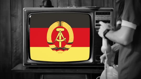 East German Flag on Old TV and Young Man with Retro Telephone