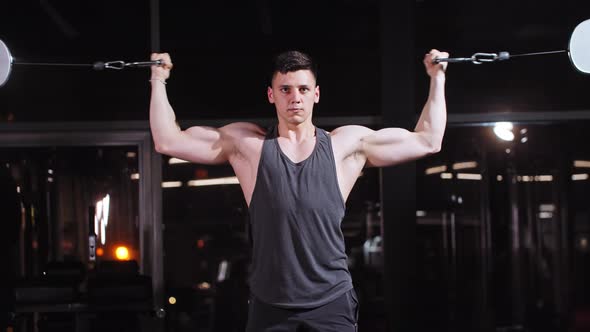 Handsome Fit Young Man Training His Hands Muscles with an Exercise Equipment in the Gym