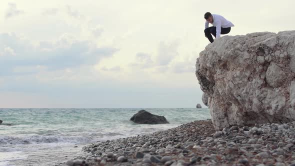 Man Sitting on the High Hill of Rock and Enjoying Amazing View of Seaside