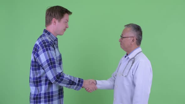 Happy Mature Japanese Man Doctor with Young Man Shaking Hands Together