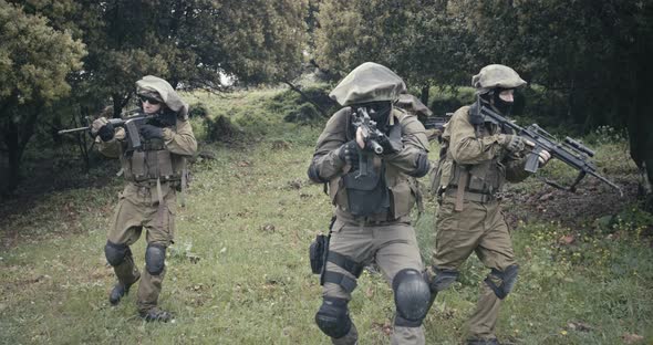 Squad of fully armed commando soldiers during combat in a forest scenery