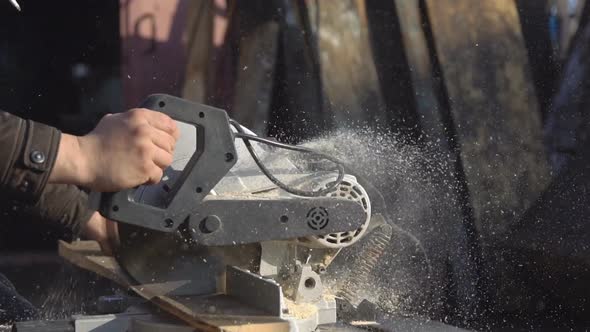 Man Saws a Wooden Board with a Saw