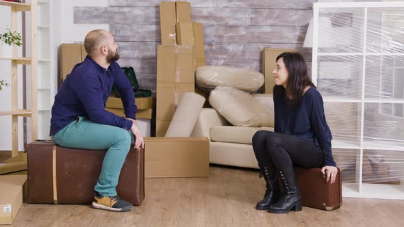 Couple Talking and Sitting on Suitcases After Carrying Boxes