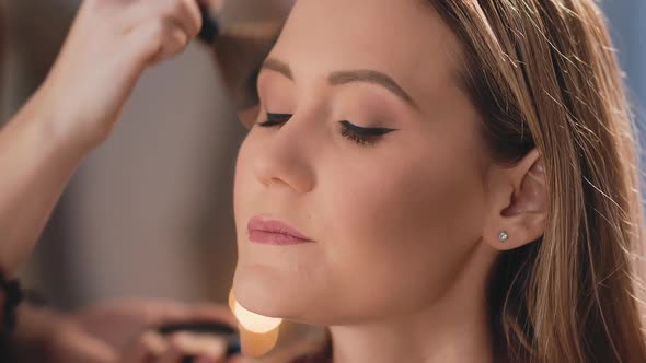 Make-up Artist Finishes Makeup By Applying Powder with a Professional Brush on the Face of a