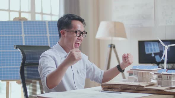 Side View Of Asian Man Being Happy Succeed Building A Model Of Small House With Solar Panel