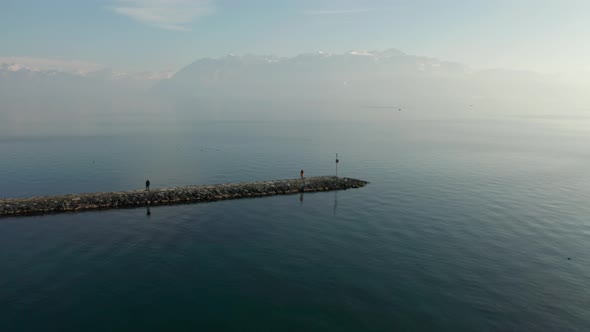 Aerial of woman standing on stone quay at lake Geneva, Switzerland