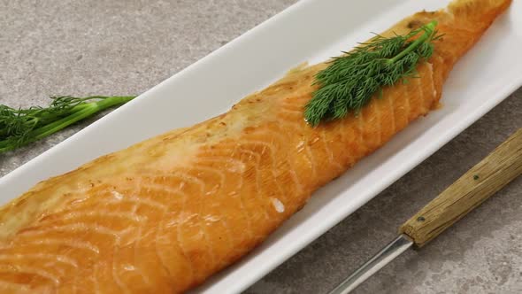 Smoked salmon filled tail part on a dish  with fresh dill close up 