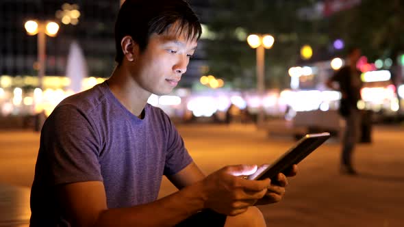 Young man working on tablet computer at night 