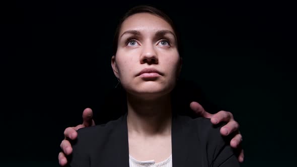 The hands of an unknown man lie on the shoulder of a young woman in a jacket