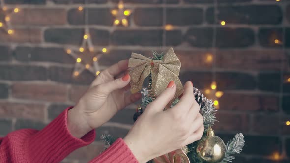 Woman Touches Golden Bow on Top of Decorated Christmas Tree
