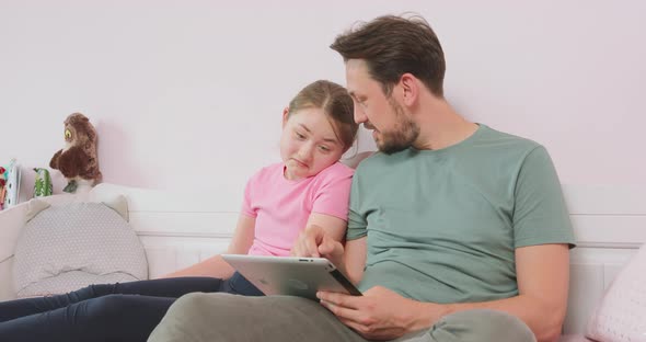 Father and Teen Daughter Sitting on the Sofa in Living Room Browsing the Online Store Enjoying