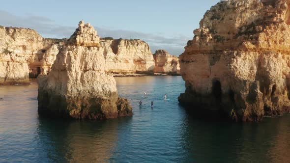 Sup Surfers Paddleboarding Between Rock Formations of Ponta De Piedade Portugal