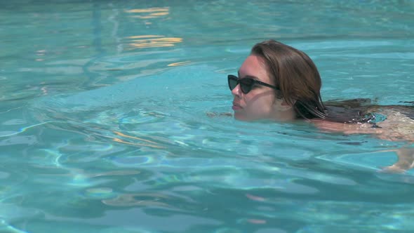 Beautiful toned young woman in black bikini swimming  in crystal clear water