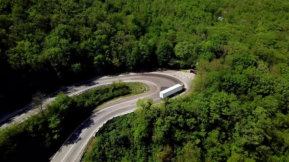 FPV Semi Truck Driving Along Mountain Road Going Through Forest Landscape