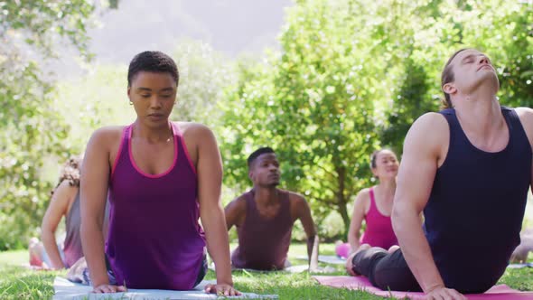 Group of diverse young people meditating and practicing yoga together at the park