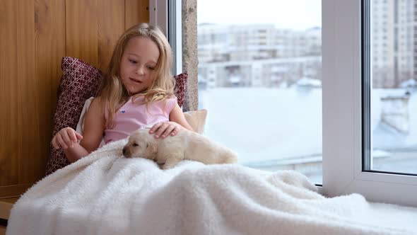 Girl Sitting on Windowsill with Labrador Puppy