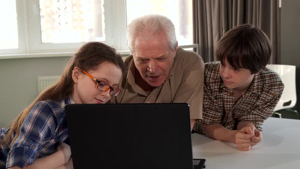 Children and Their Grandpa Watching Something on Laptop