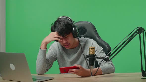 Upset Man With Headphone Losing Mobile Phone Game While Shooting Video By Camera On The Green Screen