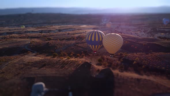 Two Hot Air Balloons Fly Closely to Each Other Over Meadow in Cappadocia Turkey