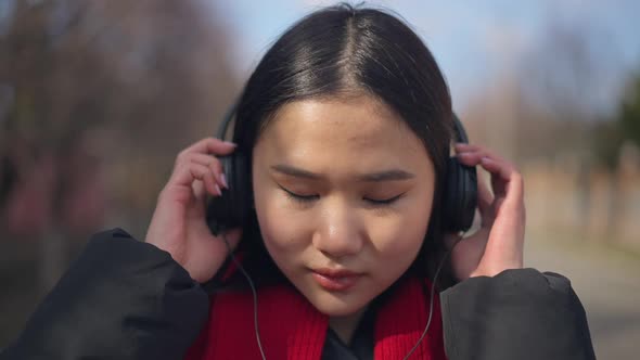 Closeup Face of Cheerful Asian Young Woman Taking Off Headphones Smiling Looking at Camera in Slow