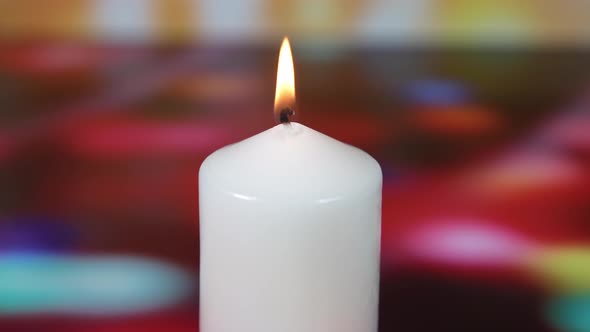 White Candle Is Burning On Colorful Background.  Zooming In