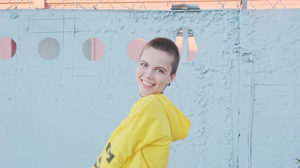 Portrait of Dancing Smiling Young Woman with Short Hair in Industrial City Background at Sunset