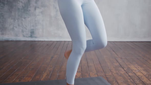 Young and sporty girl in sportswear is doing exercises at home using virtual reality helmet.