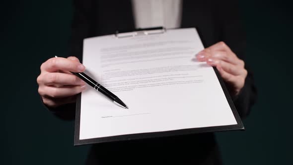 The manager indicates the place in the contract where to sign. Close-up