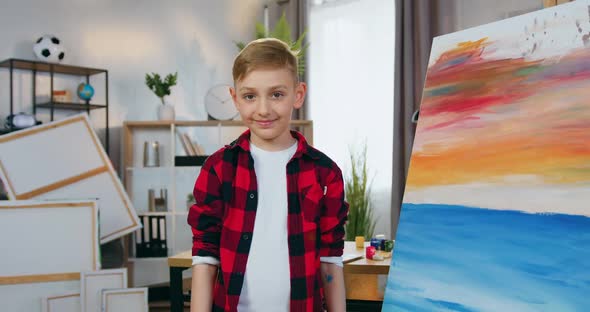 Boy Posing on Camera in Painting Workshop and Showing Many Paintbrushes Into Camera