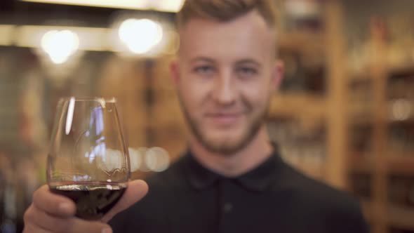 Portrait of Handsome Man Raising His Wine Glass Closeup. The Focus Moves From the Wine Glass