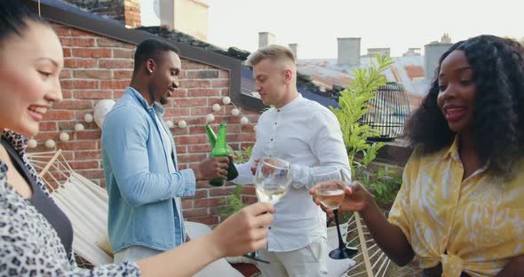 Friends Having Fun Together on Balcony, Drinking Beer and Wine and Smiling Lots During Summer Party