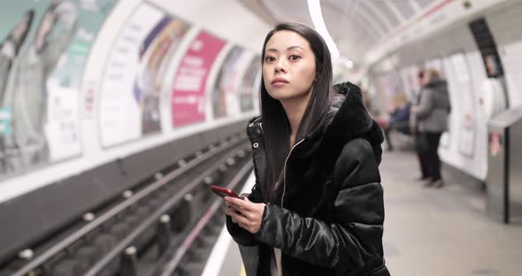 Chinese woman waiting in underground station using smartphone