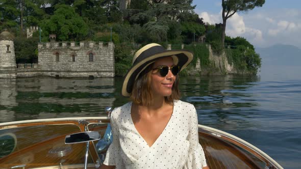 A woman on a classic luxury wooden runabout boat on an Italian lake