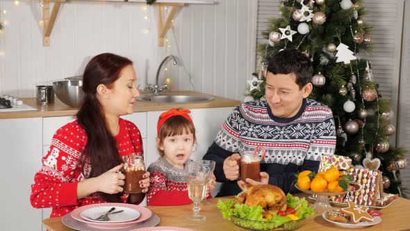 Father Feeds Daughter Sitting with Wife at Festive Table