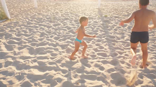 Happy Children Run on the White Sand of the Beach in the Setting Sun