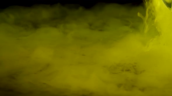 Yellow Smoke Dry Ice on a Black Surface. Closeup. Slow Motion