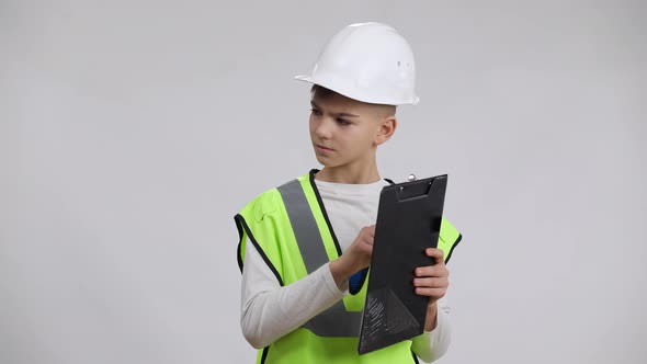 Concentrated Little Foreman in Helmet Standing Paperwork Looking Around Gesturing