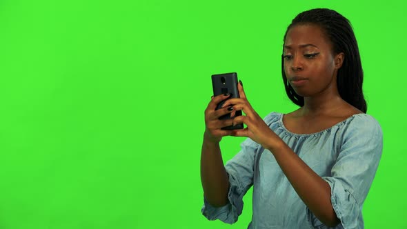 A Young Black Woman Takes Pictures of Something Off the Camera with a Smartphone