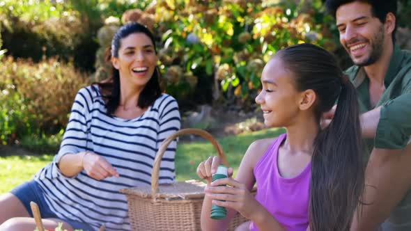 Girl blowing bubble while her parents sitting in background 4k