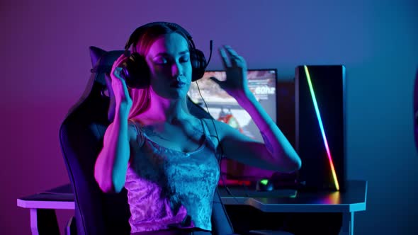 Tattooed Gamer Girl Sitting By the PC - Putting on Her Headphones and Turns To the Monitor