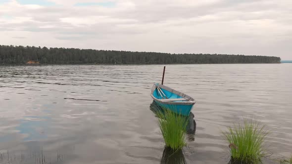 Old Blue Wooden Boat Anchored Off the Coast of the Bay Sways on Calm Waves