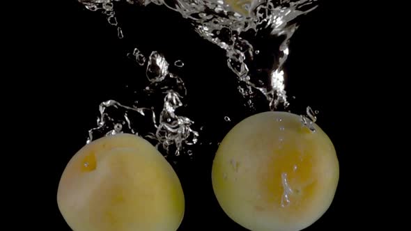 Super slow motion, fresh apricots fall into the water