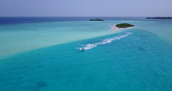 Ski jet speeding around tranquil lagoon tracing and foaming over turquoise water near tropical islan