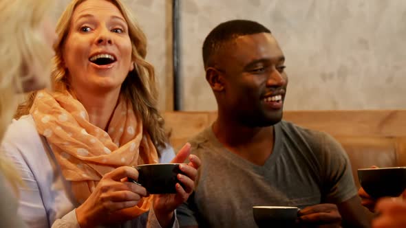 Group of happy friends interacting while having coffee in the restaurant 4K 4k