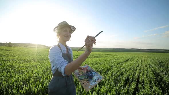 Woman artist painting with oil paints in a field