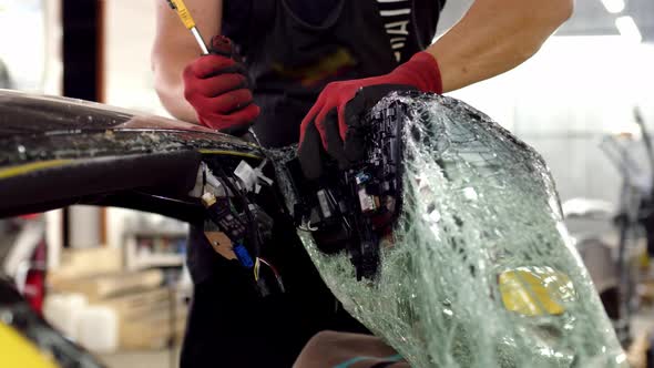 Mechanic Dismantles Broken Glass on Bright Yellow Car in Service