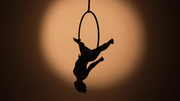 The Black Silhouette of an Aerial Gymnast Performing Acrobatic Tricks and Spinning in the Air on the